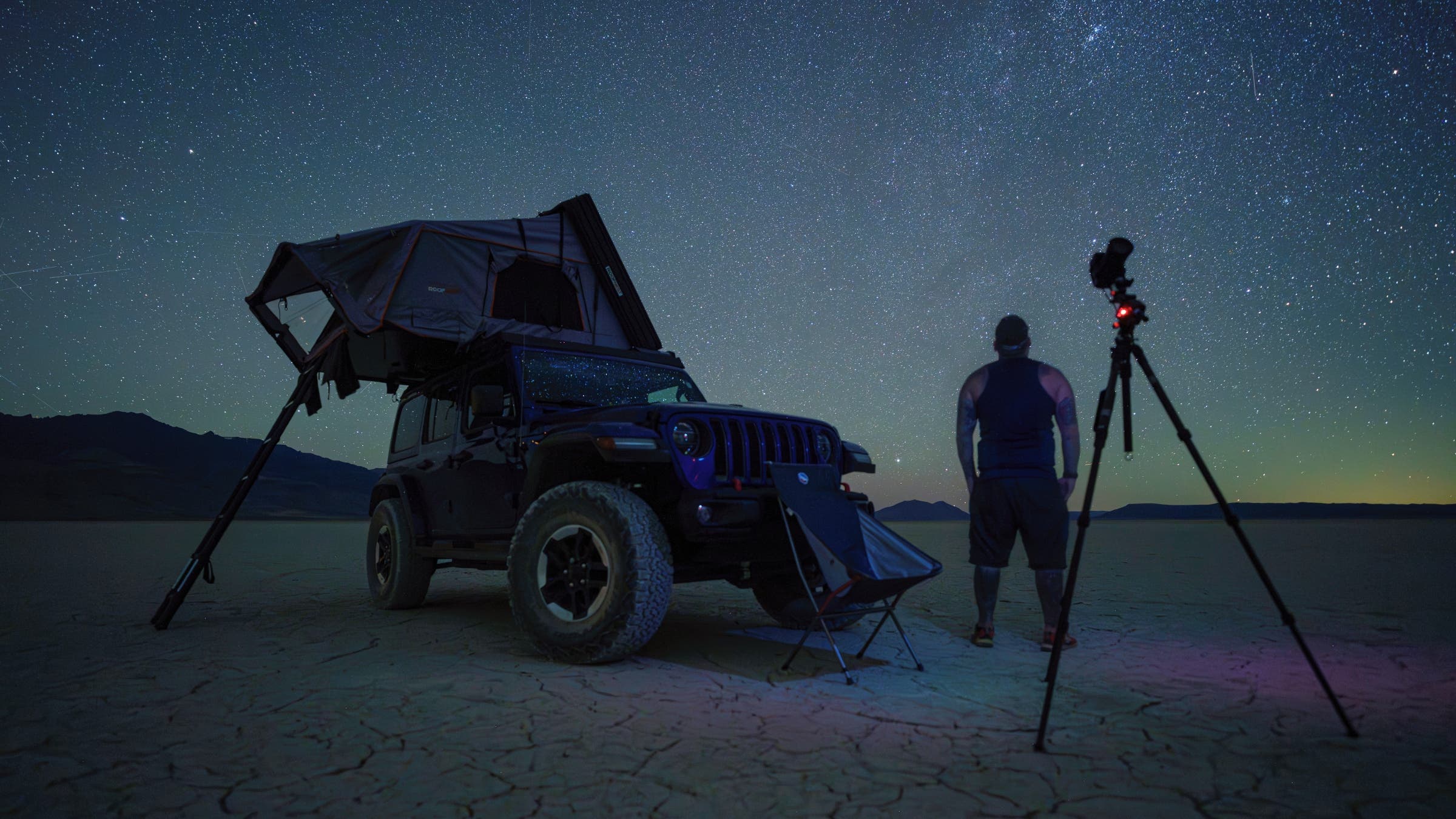 Man photographing a clear night sky on a dry lakebed.