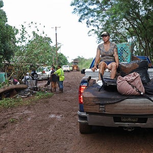 A woman sits on the back of a pickup carrying a ruined mattress and other home effects after the Kona Low storm flooding that devastated the Otake Camp community in Waialua, Hawaii