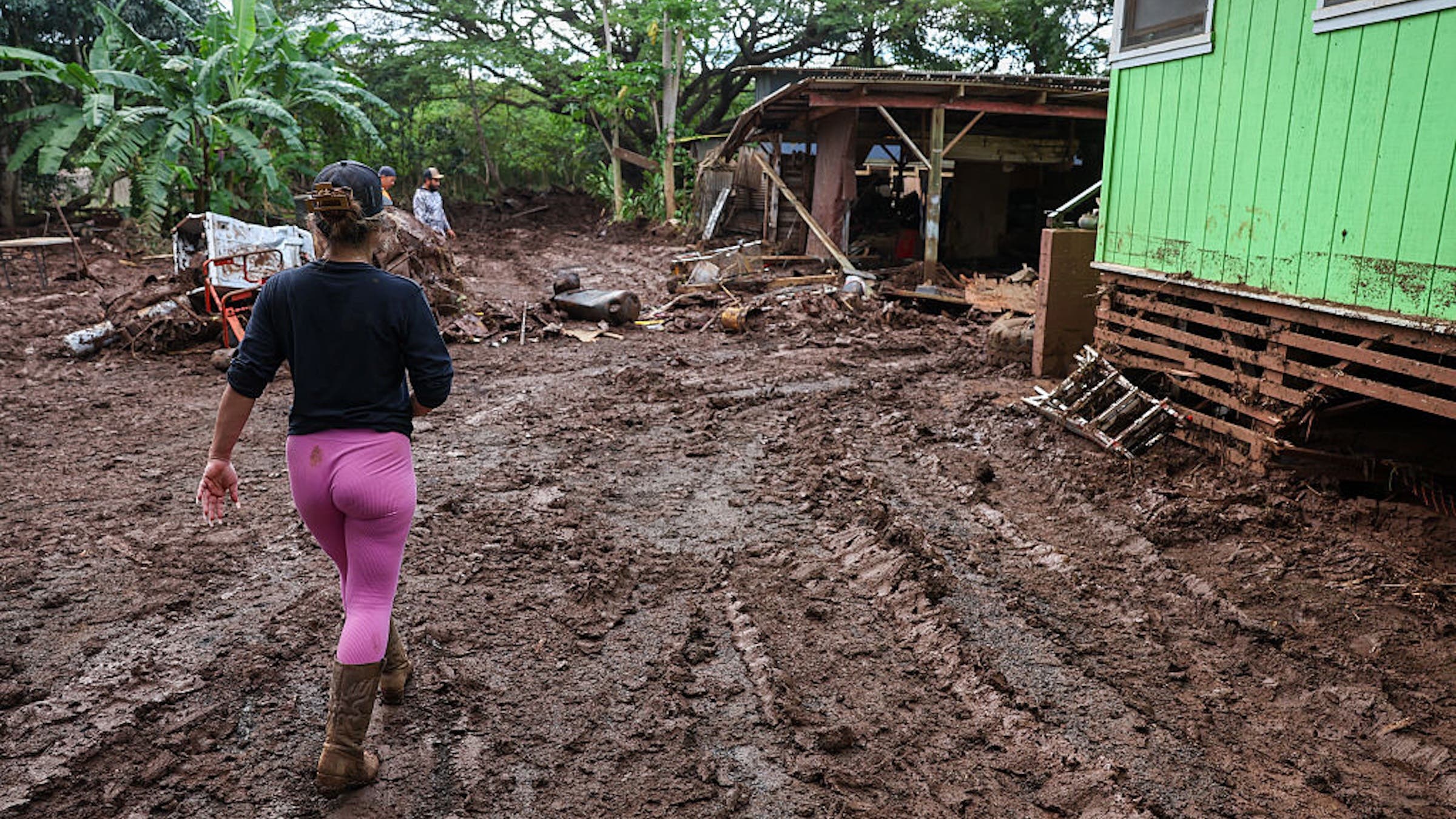 Residents and volunteers work on cleaning up after the Kona Low storm flood that devastated the Otake Camp community