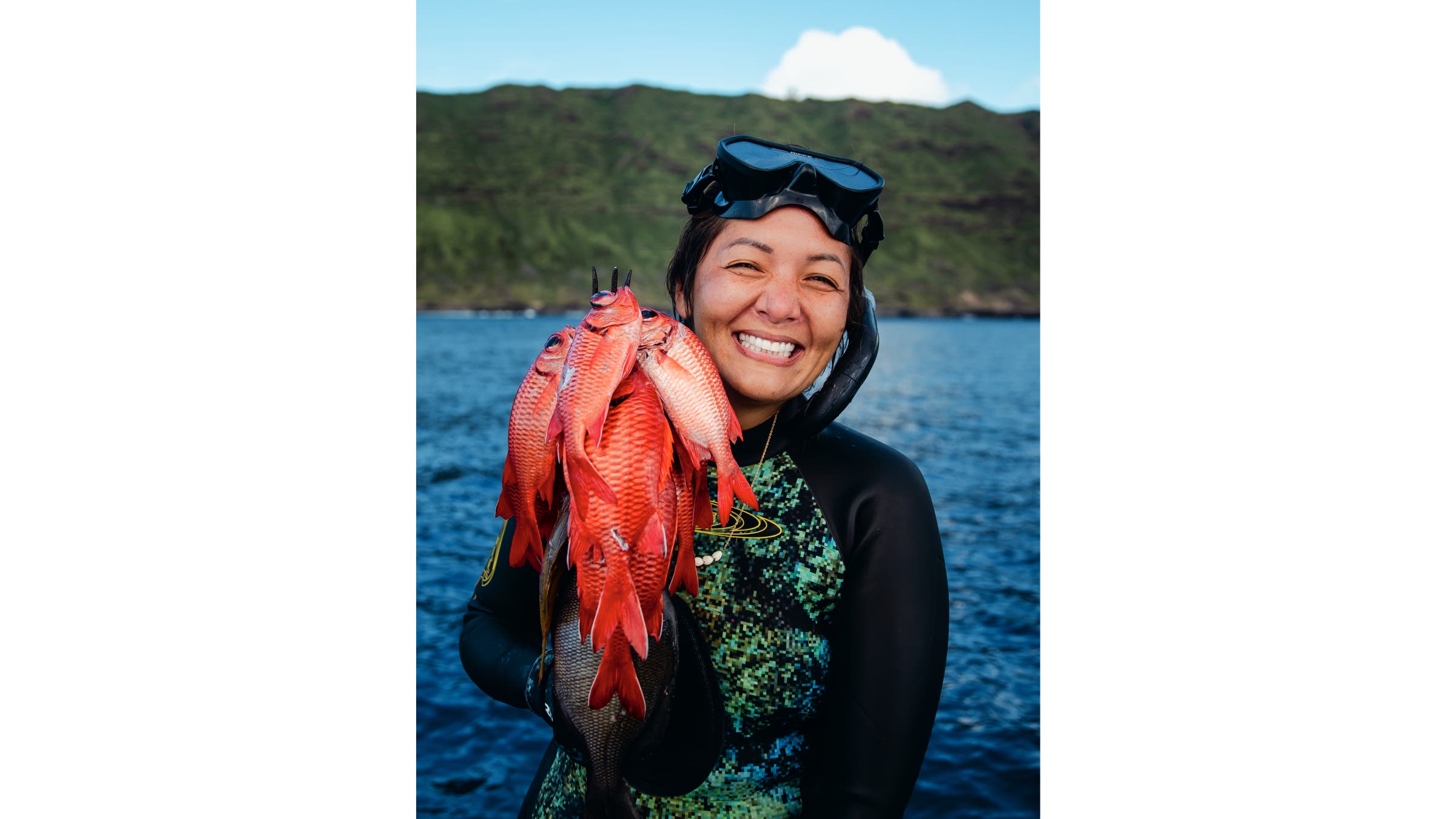 Kimi Werner holding up a fresh catch of several red snapper on a spear.