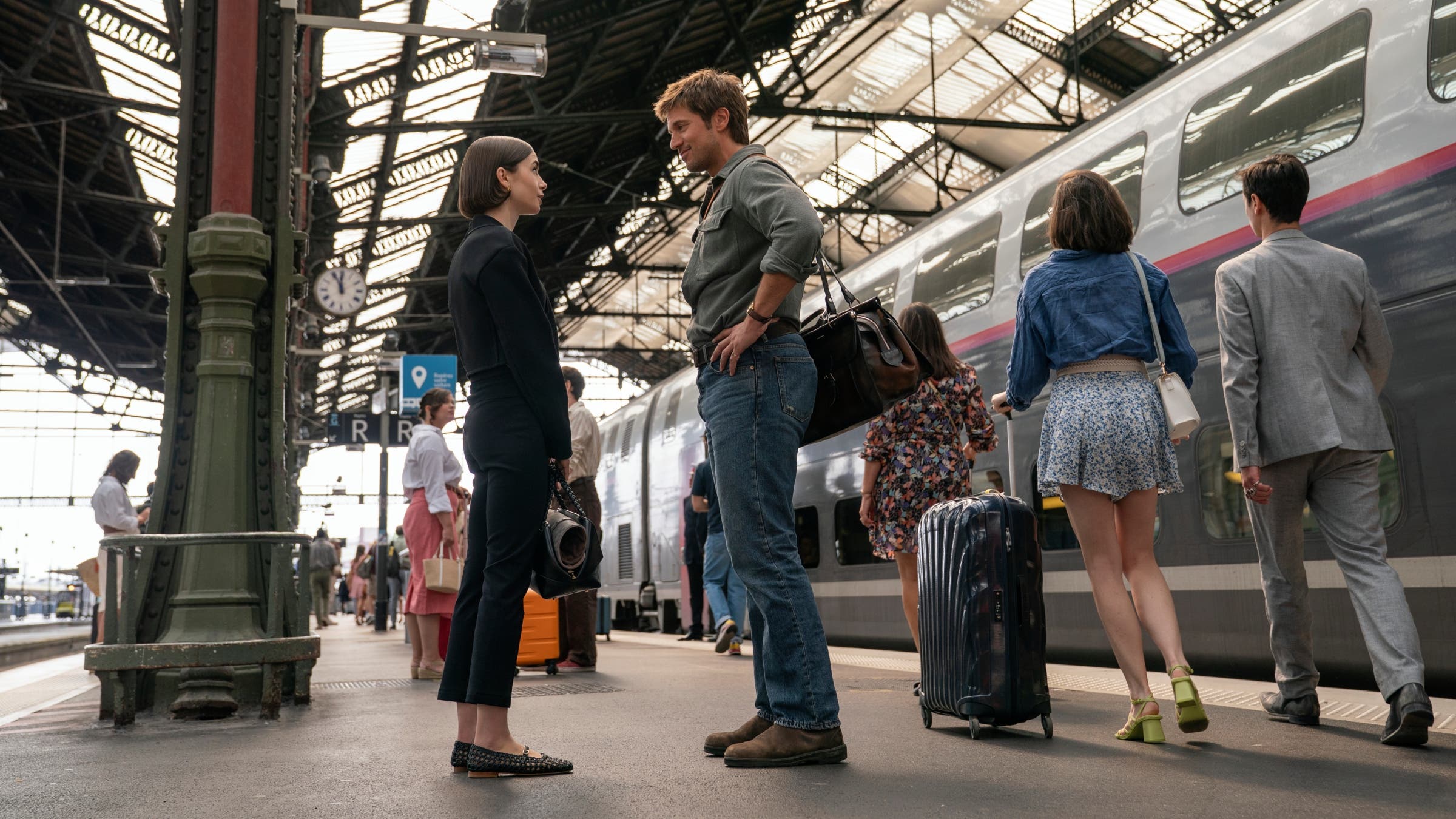 A man and a woman talk to each other at a train station.