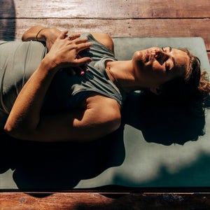 woman lies on yoga mat in the sun preparing for sleep, representing one of the top 2026 health and wellness trends