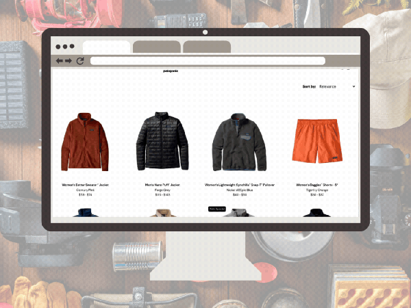 A desktop computer screen displays the Patagonia Worn Wear website, featuring a grid of various used outdoor gear such as puffer jackets, fleece pullovers, and hiking shorts. The monitor is set against a background of organized camping equipment, including ropes, a headlamp, and a water bottle.