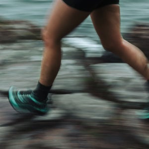 Close-up of a runner's legs running a trail race in bad weather.