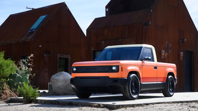 Orange Slate truck in front of rustic buildings.