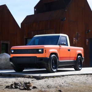Orange Slate truck in front of rustic buildings.