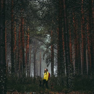 woman standing in yellow jacket in woods