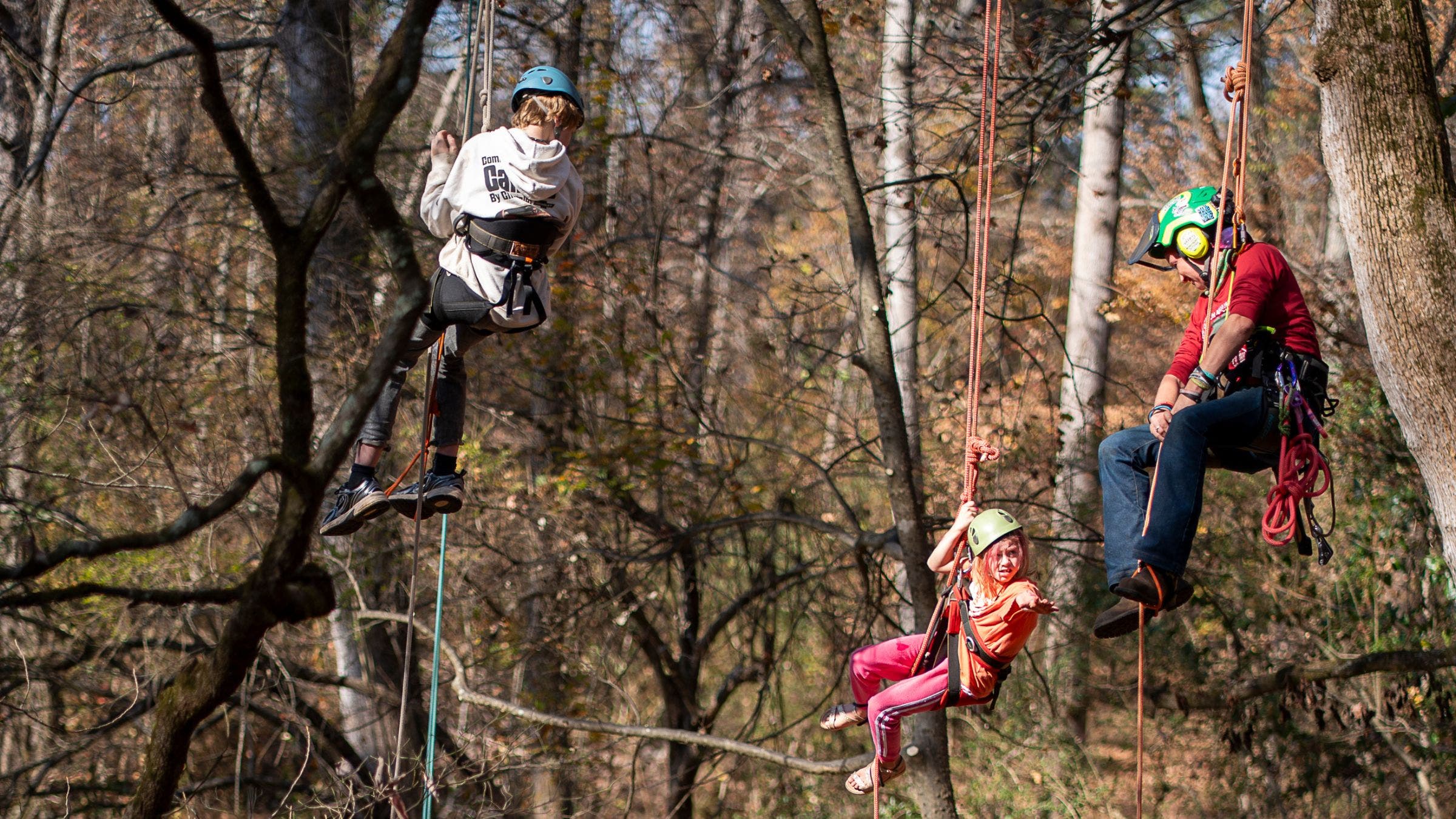 three people hang from a tree