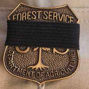 A black mourning band covers the badge of a U.S. Forest Service officer during a memorial service for fallen Big Bear Interagency Hotshot Charles Morton, a firefighter who was killed battling the El Dorado wildfire, on September 25, 2020 in San Bernardino, California