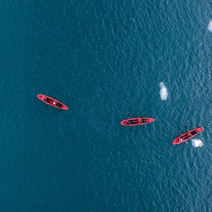 A sea kayak floating in the icy blue waters of Svalbard, Norway, near a rocky coastline