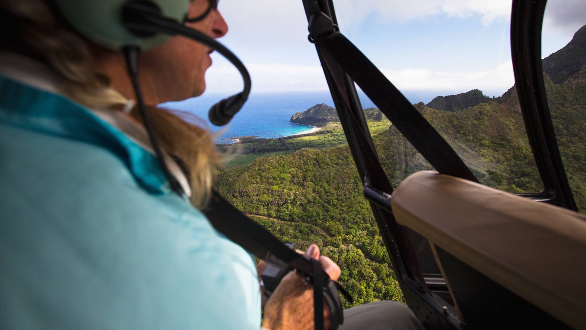 A woman enjoys views of Kauai from a helicopter.