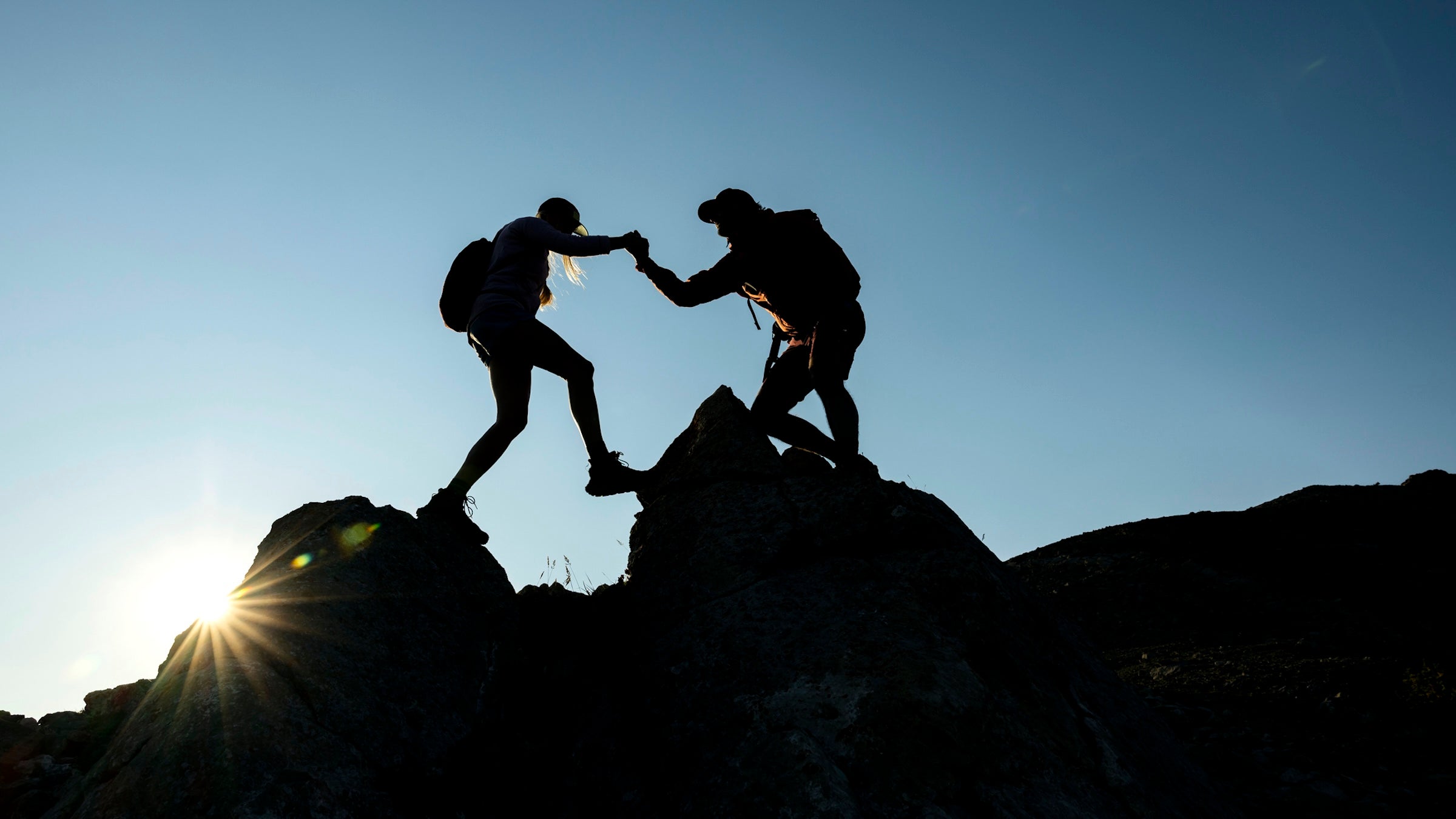 A couple is shown against the blue sky hiking over rocks. Great Smoky Mountains issued a warning asking visitors to be careful