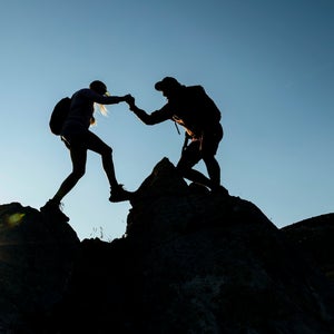 A couple is shown against the blue sky hiking over rocks. Great Smoky Mountains issued a warning asking visitors to be careful