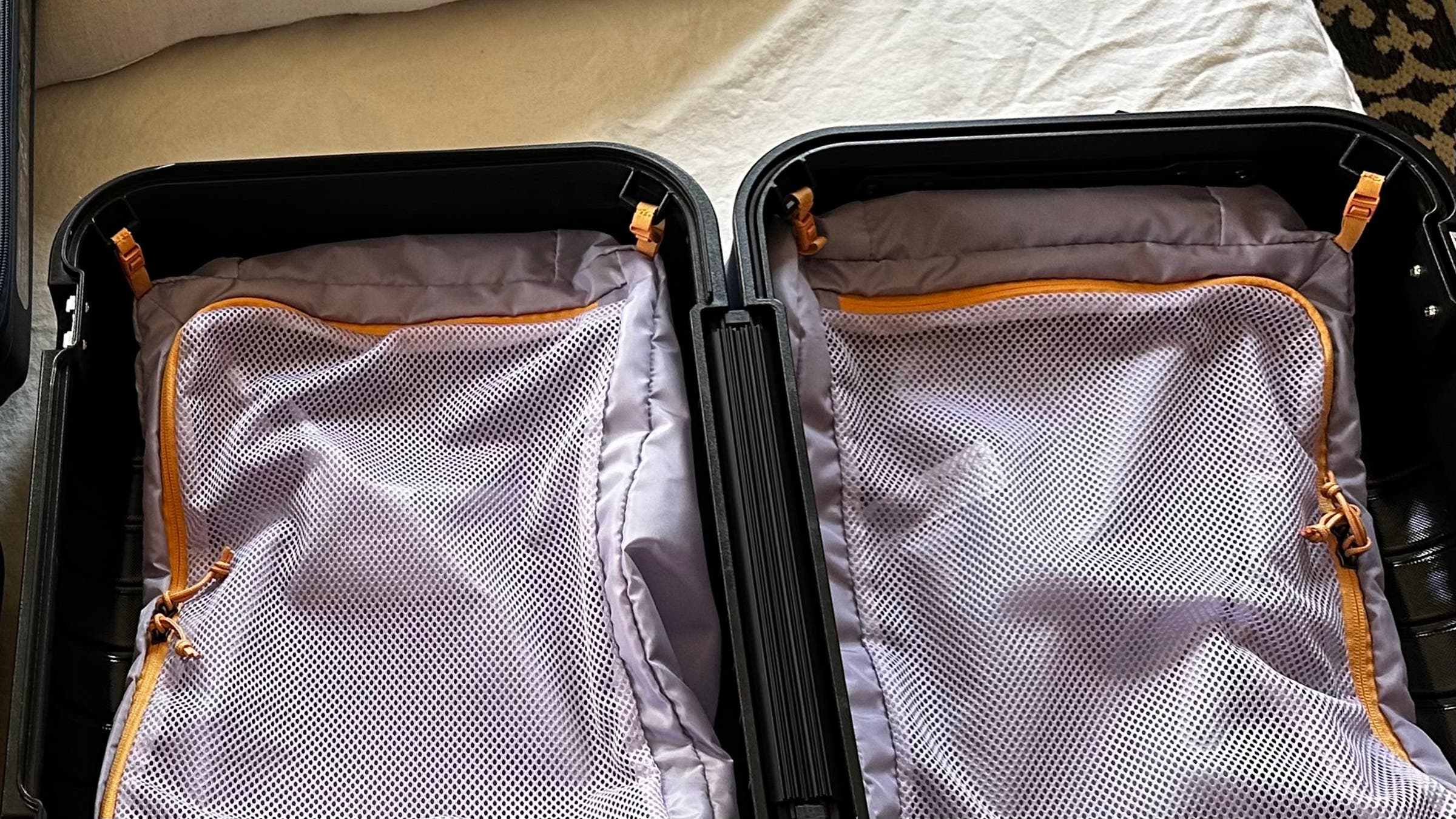 Cotopaxi hard-sided carry on suitcase opened up to show internal packing system and mesh organizers, with nothing packed yet inside.