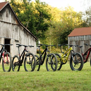 Multiple trail mountain bikes lined up in a row on grassy field during Pinkbike's 2026 Field Test