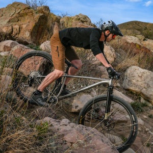 Mountain biker rides downhill on a mountain bike with 32 inch tires.
