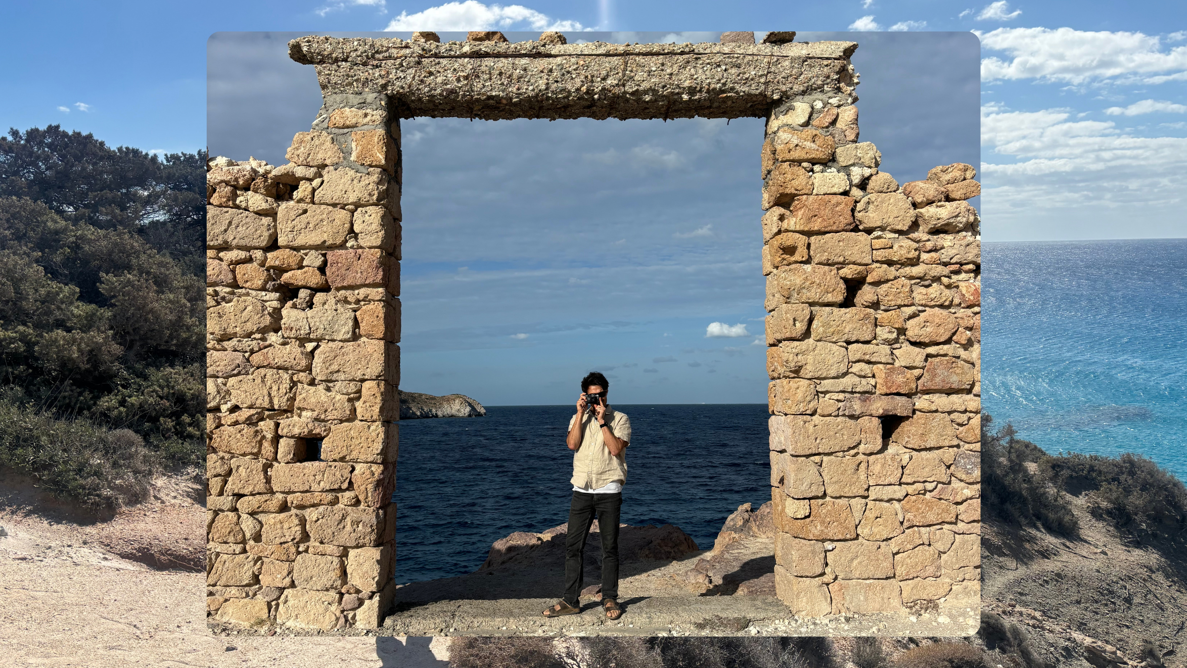 man taking photo with a film camera on the shoreline in Greece, framed in ruins