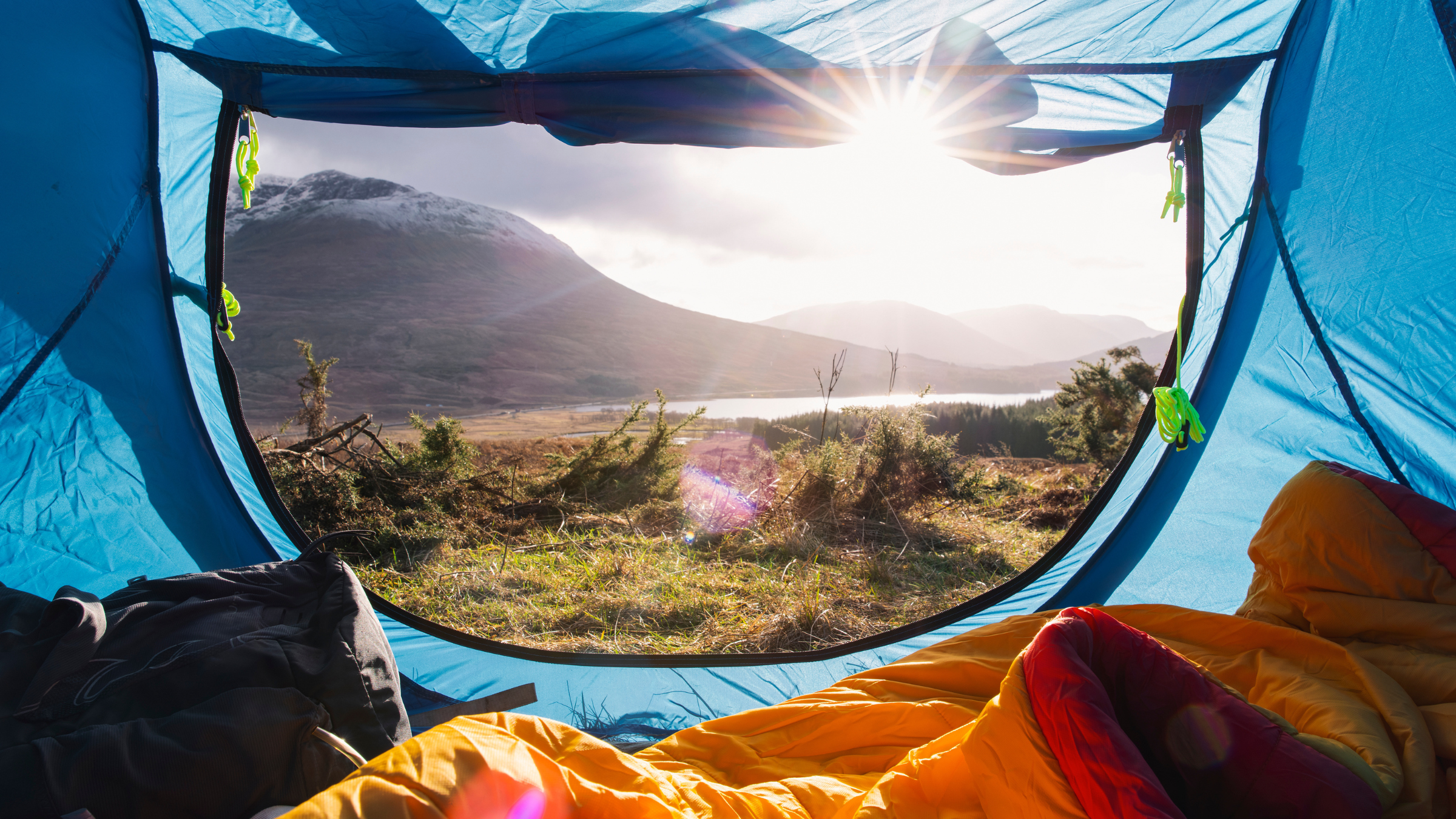 a tent open looking out on a mountain range and lake