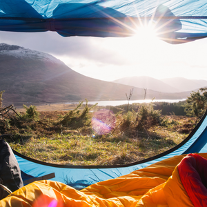 a tent open looking out on a mountain range and lake
