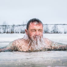 Man doing a cold plunge in an ice hole, coming up from under the water, doing a cold plunge mistake by plunging in too-cold of water