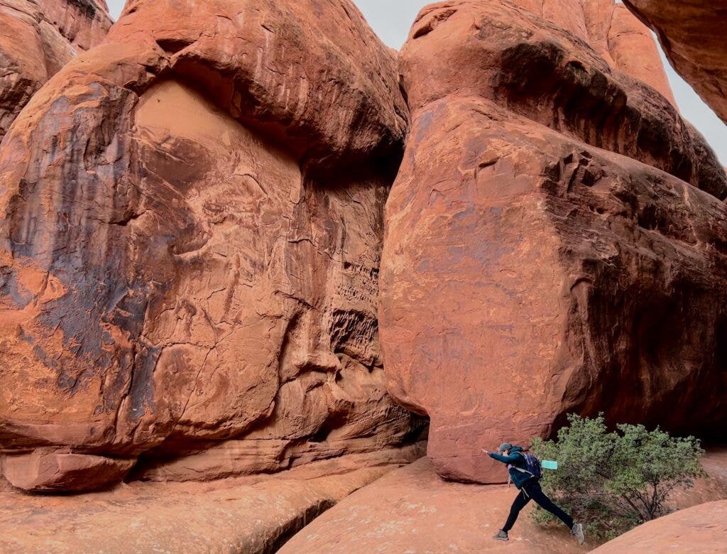 a hiker jumping over a chasm in fiery furnace