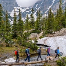 hikers crossing river on log