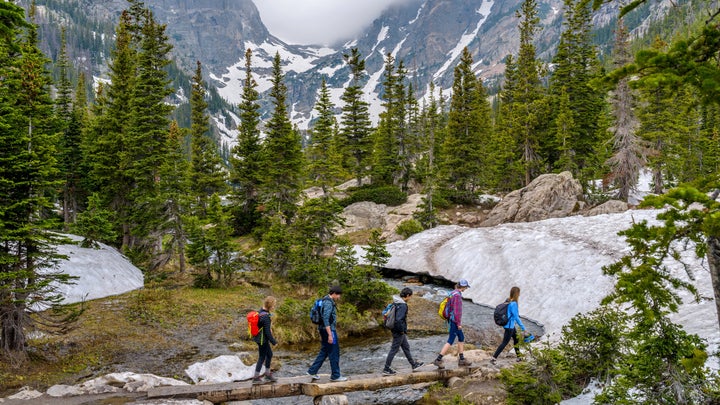 hikers crossing river on log