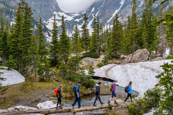 hikers crossing river on log