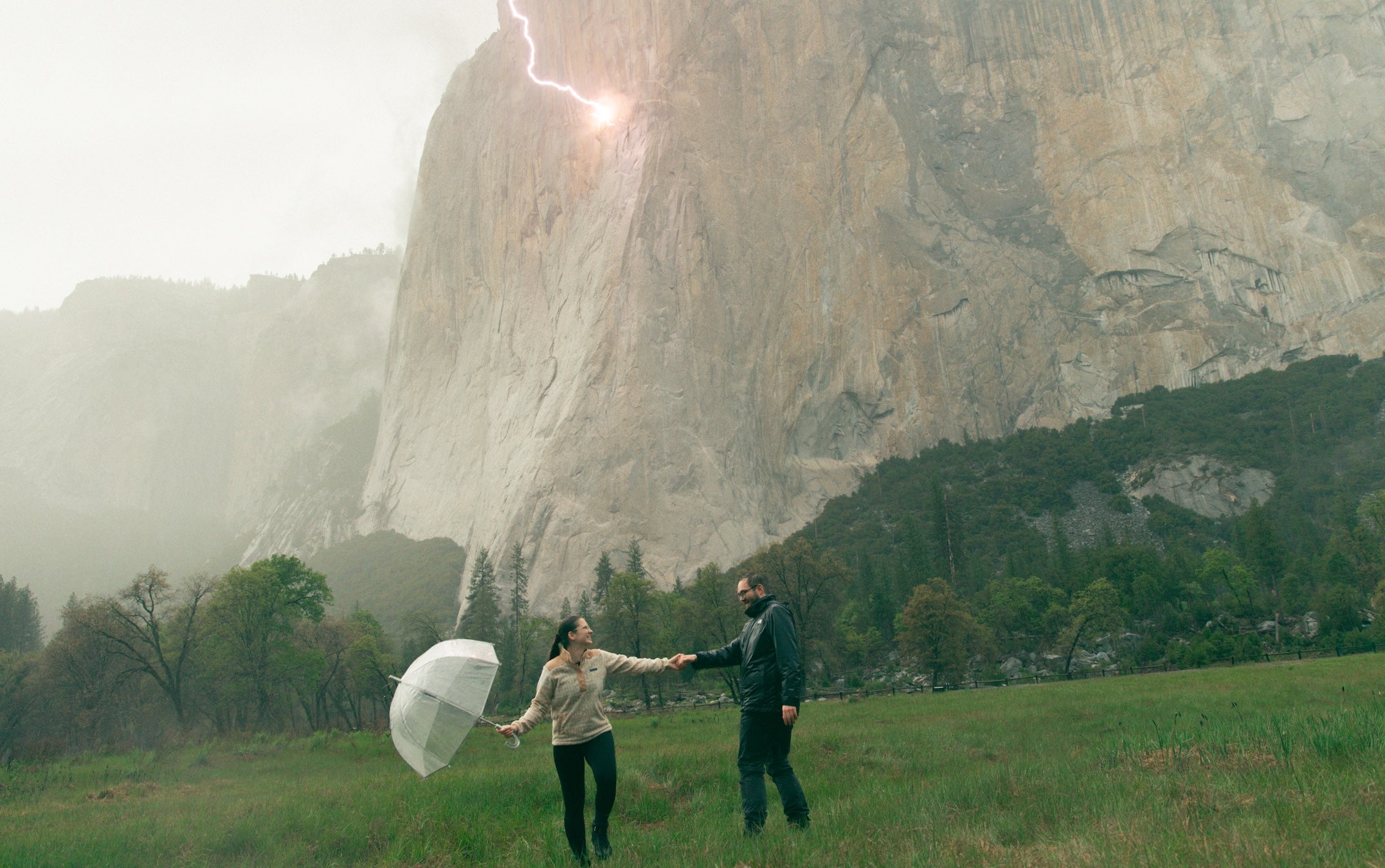 Photo captured by erica houck shows the couple with a clear umbrella holding hands in a rainstorm in front of yosemite's el capitan as a lightning bolt strikes