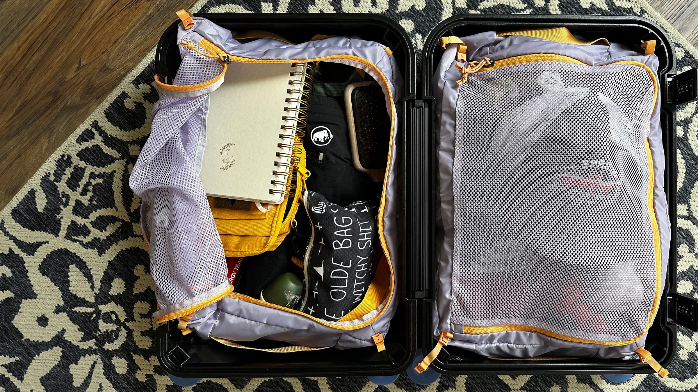 Cotopaxi hard-sided carry on suitcase opened up to show internal packing system and mesh organizers.