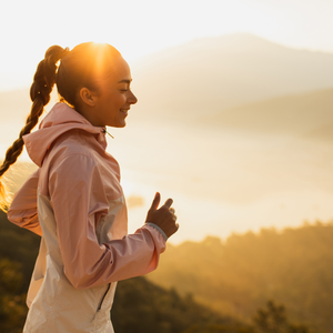 woman running at sunset on trail with mountains in the background