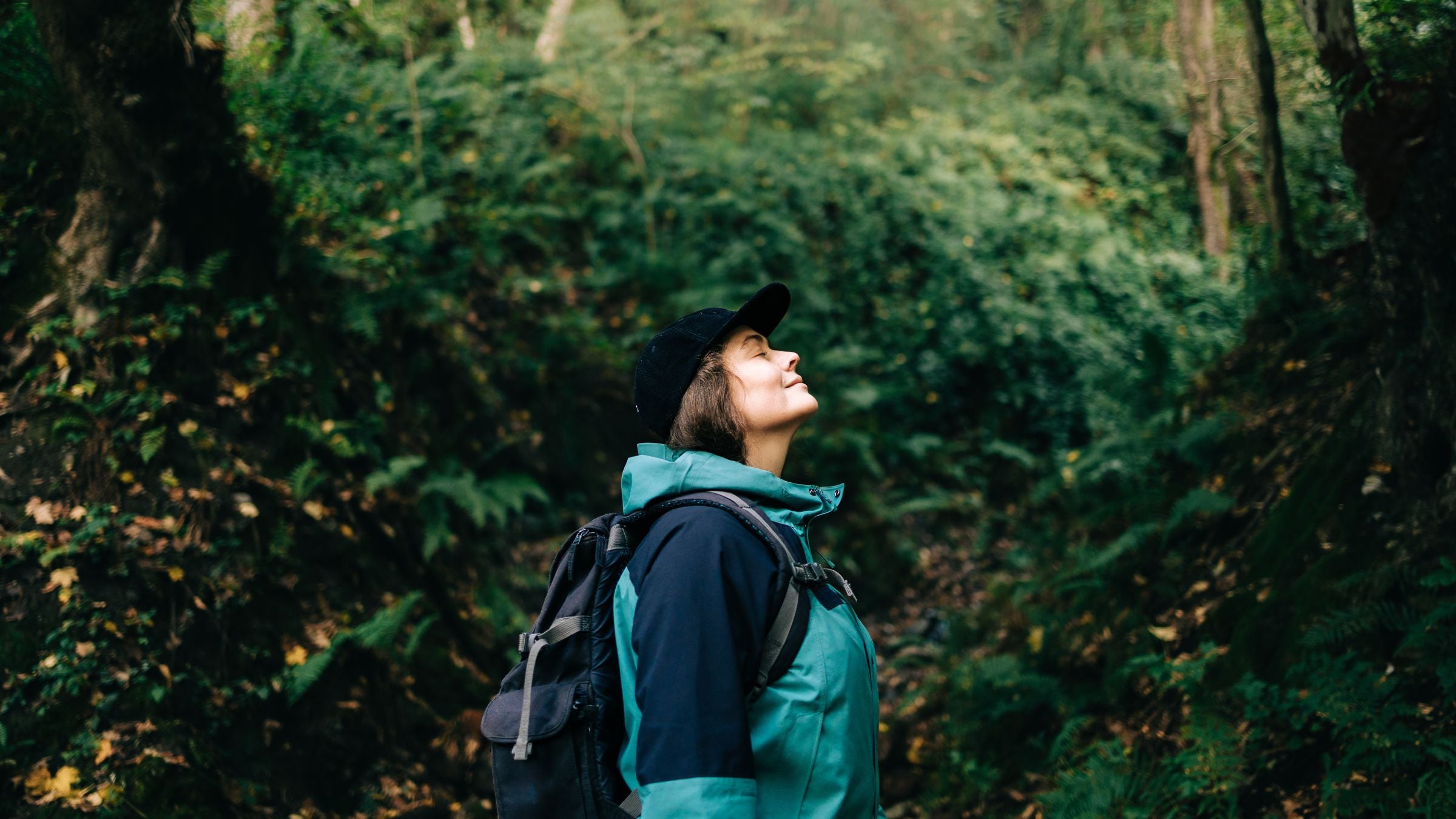 Woman enjoying serene hike in forest wilderness, representing time outside can help when you're overstimulated vs. overwhelmed