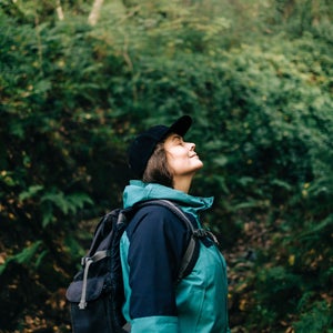 Woman enjoying serene hike in forest wilderness, representing time outside can help when you're overstimulated vs. overwhelmed