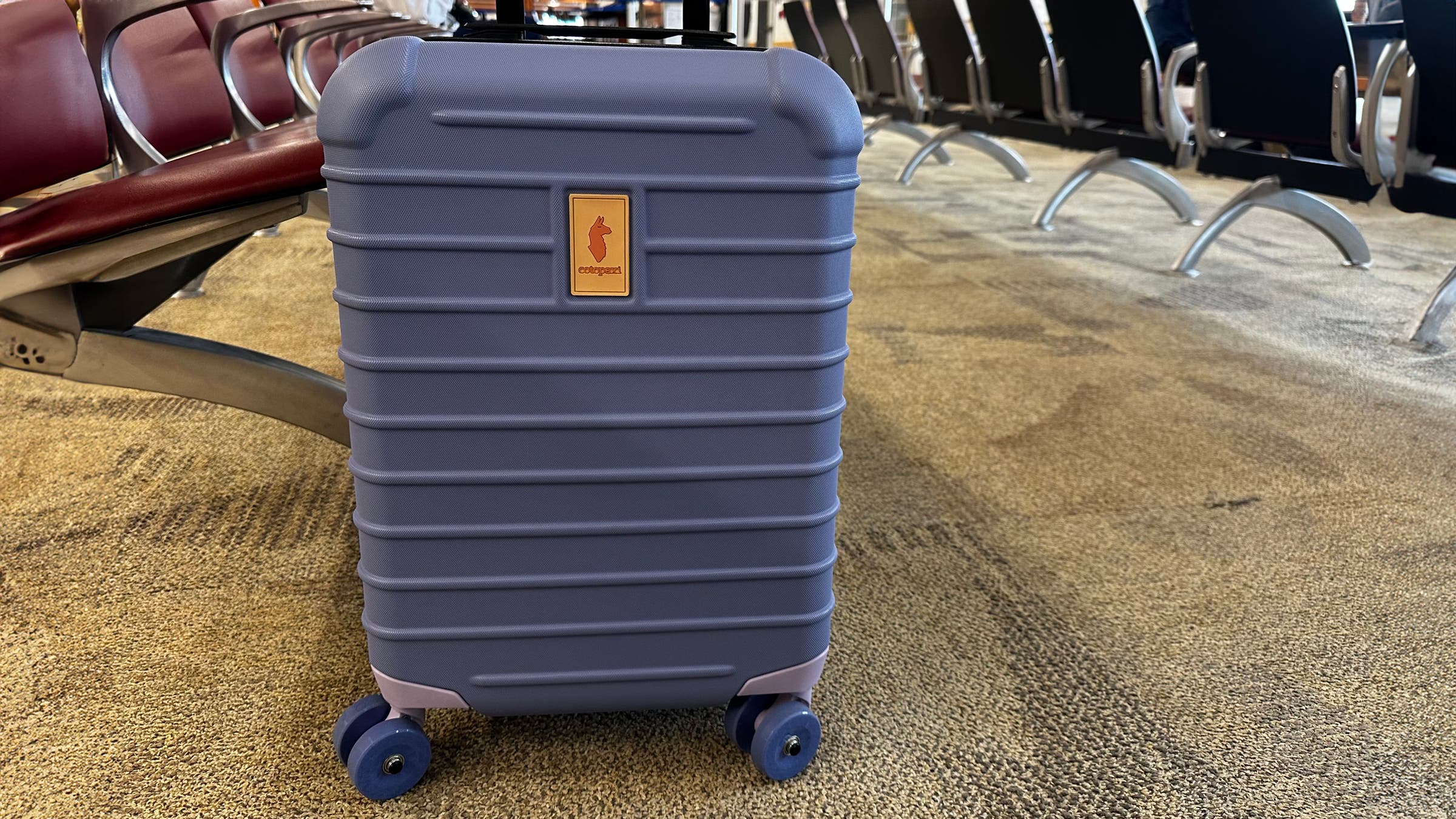 Cotopaxi hard-sided carry on suitcase has big wheels that roll smoothly through airport and over sidewalk cracks.