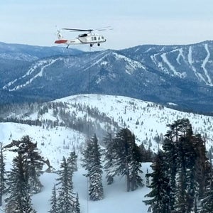 A helicopter flies over the avalanche area on February 20, three days after the slide occurred