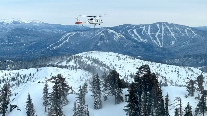 A helicopter flies over the avalanche area on February 20, three days after the slide occurred