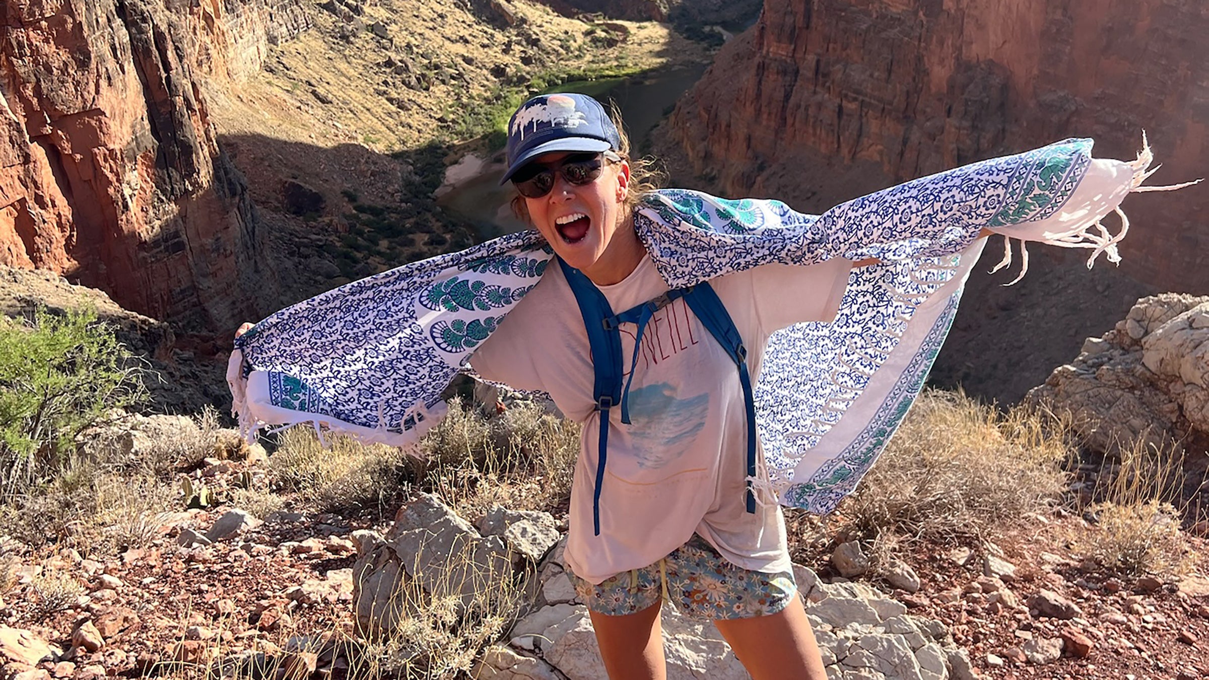 Female hiker wearing colorful and patterned sarong warp around her shoulders to keep sun off of skin.