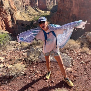 Female hiker wearing colorful and patterned sarong warp around her shoulders to keep sun off of skin.