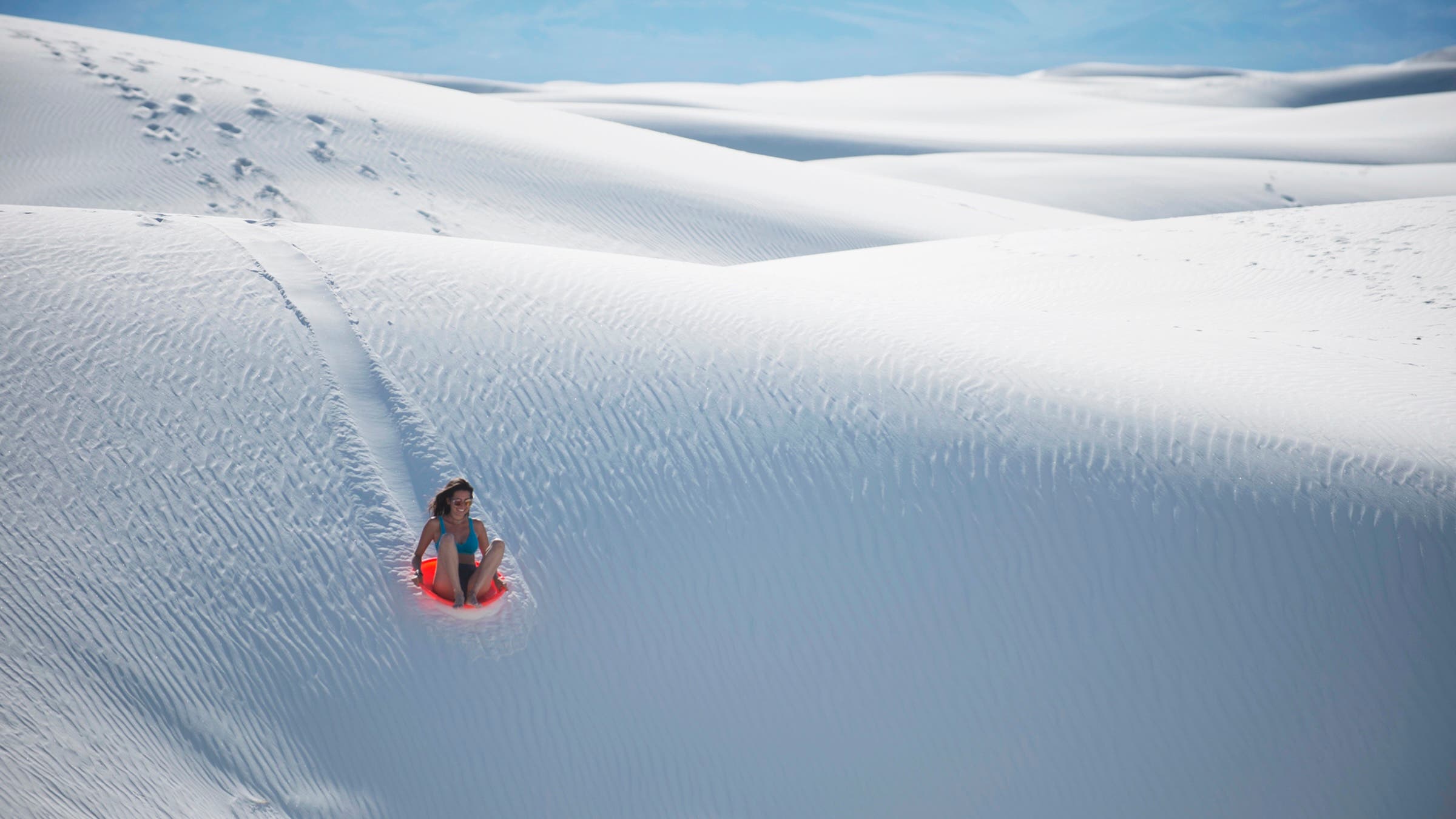 woman sledding down White Sands