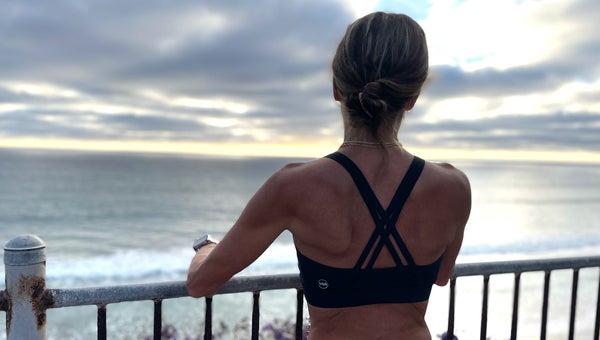 Runner standing at ocean overlook during running sports bra testing for Outside Magazine