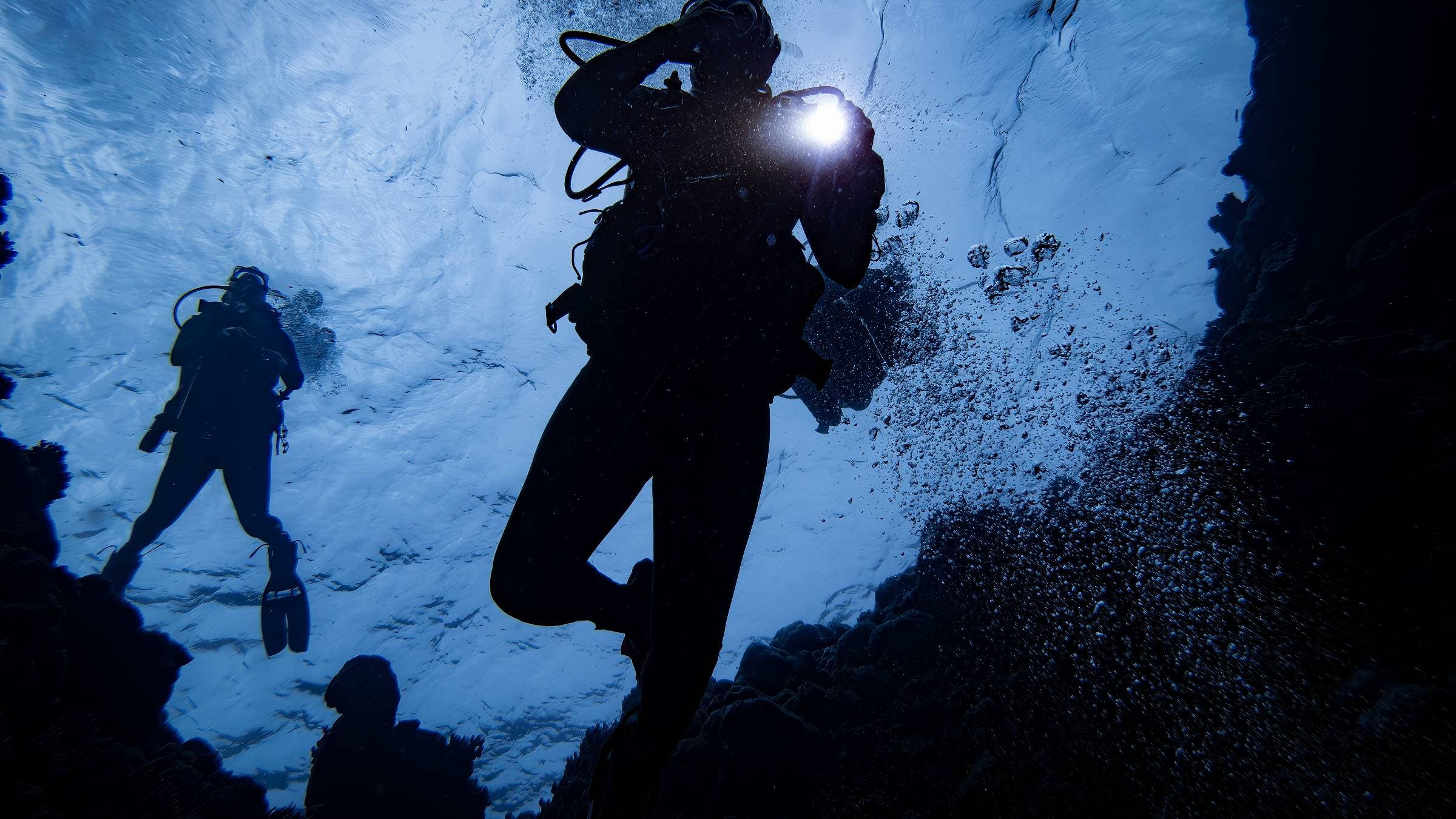 Scuba divers descending into a blue hole.