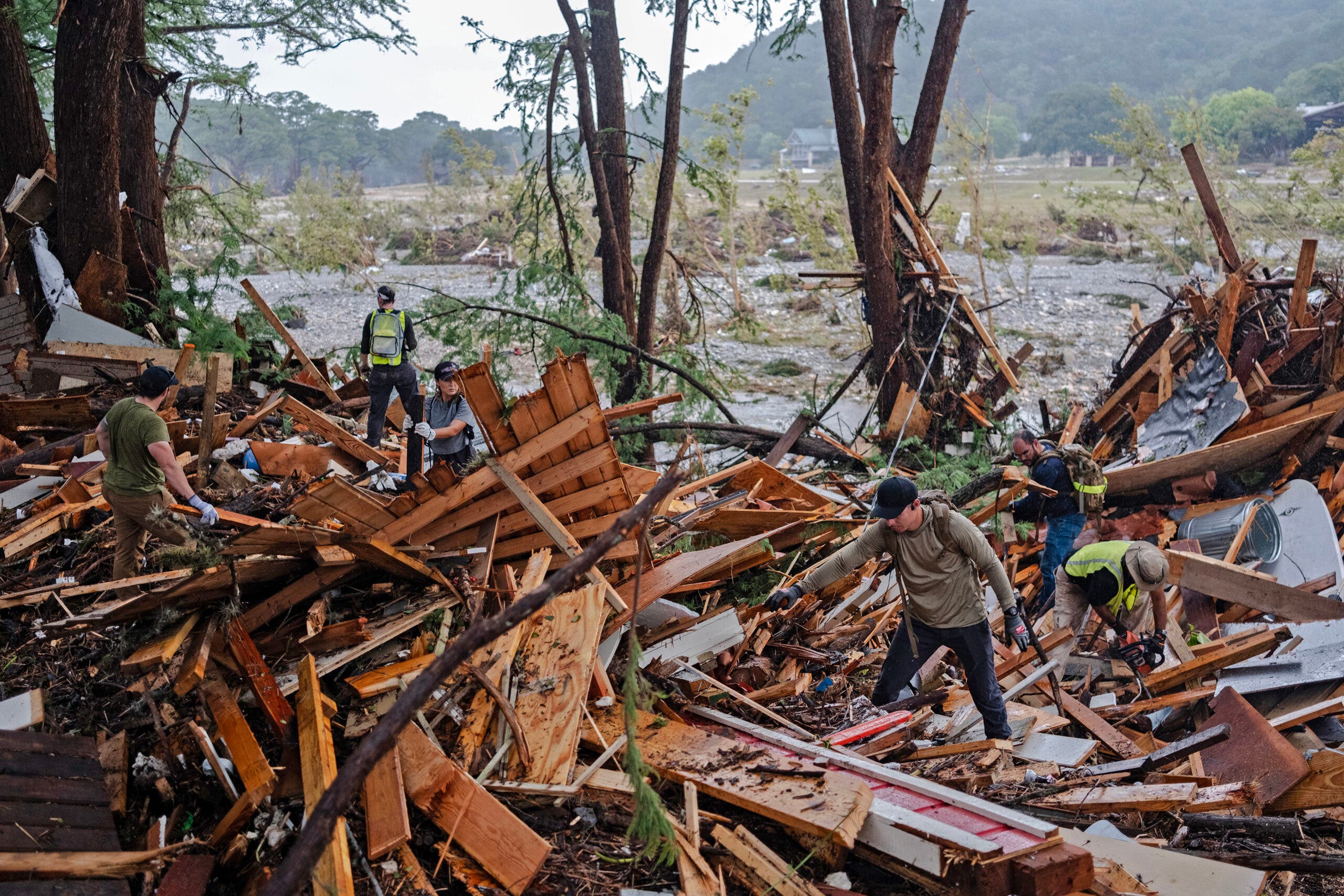 Searchers look through the remnants of smashed buildings along the banks of the Guadalupe River