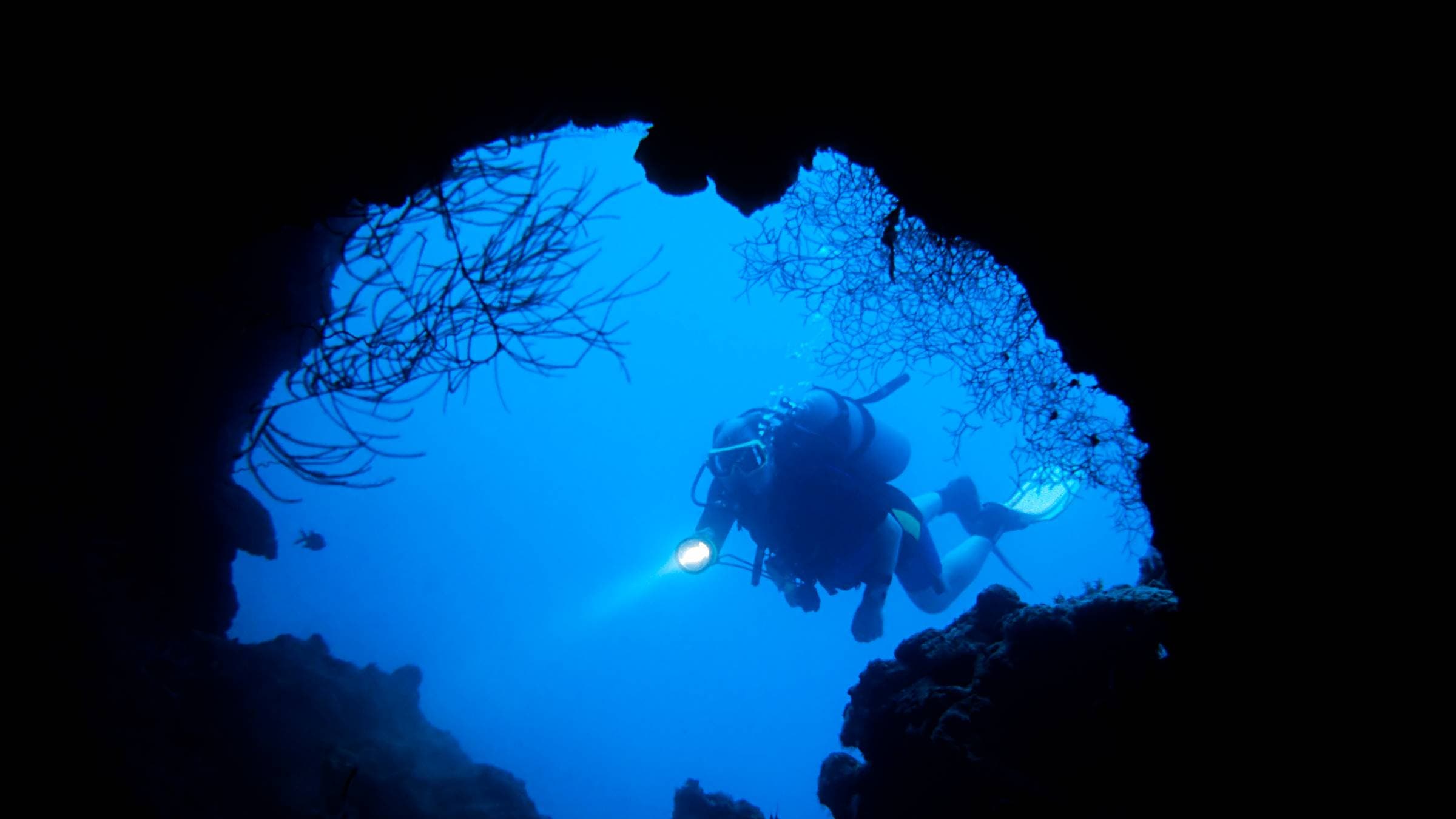 A scuba diver entering underwater cave in the Maldives.