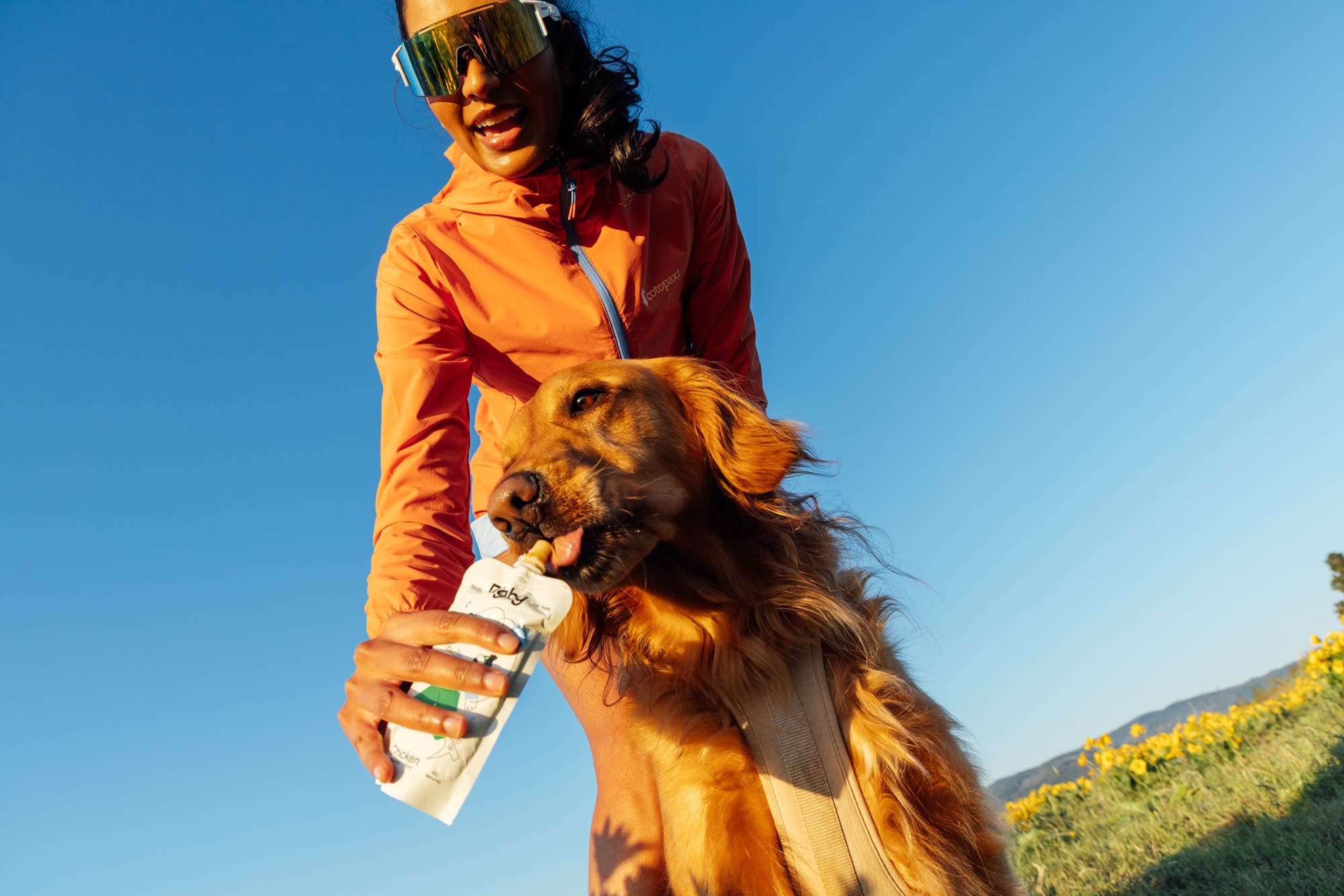 a woman hiker is shown feeding a dog with the rigby pouch in hand