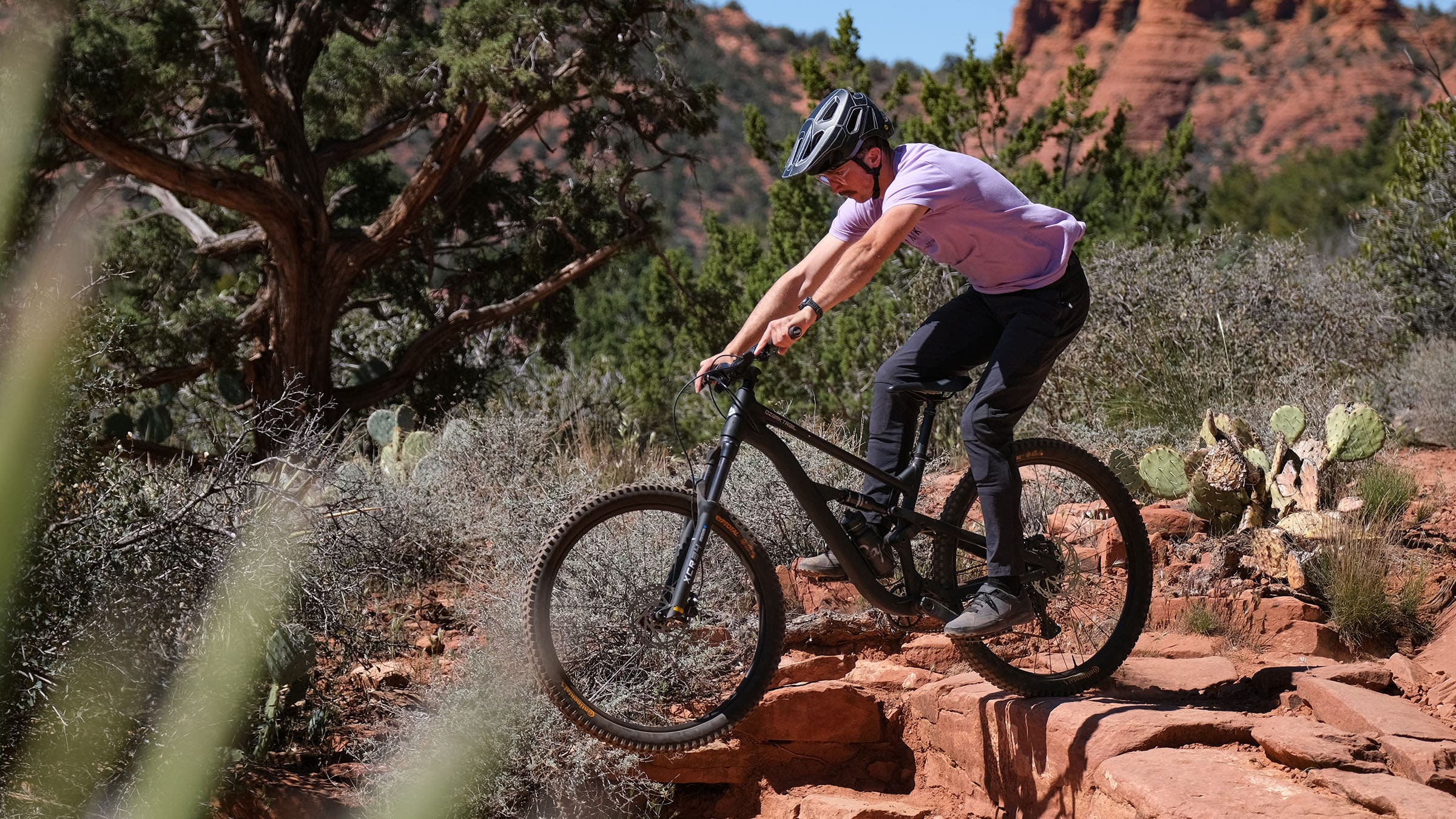 A rider on an Ozark Trail mountain bike navigates a rocky ledge drop in Sedona, Arizona