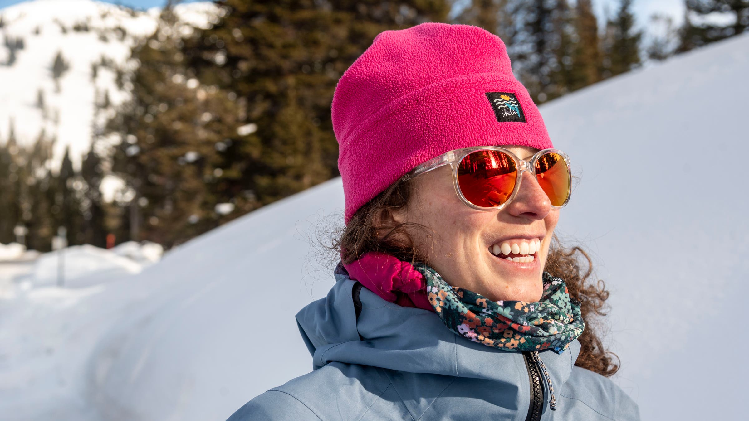 Woman wearking Vuarnet sport sunglasses while hiking in the snow, wearing Skida pink beanie.