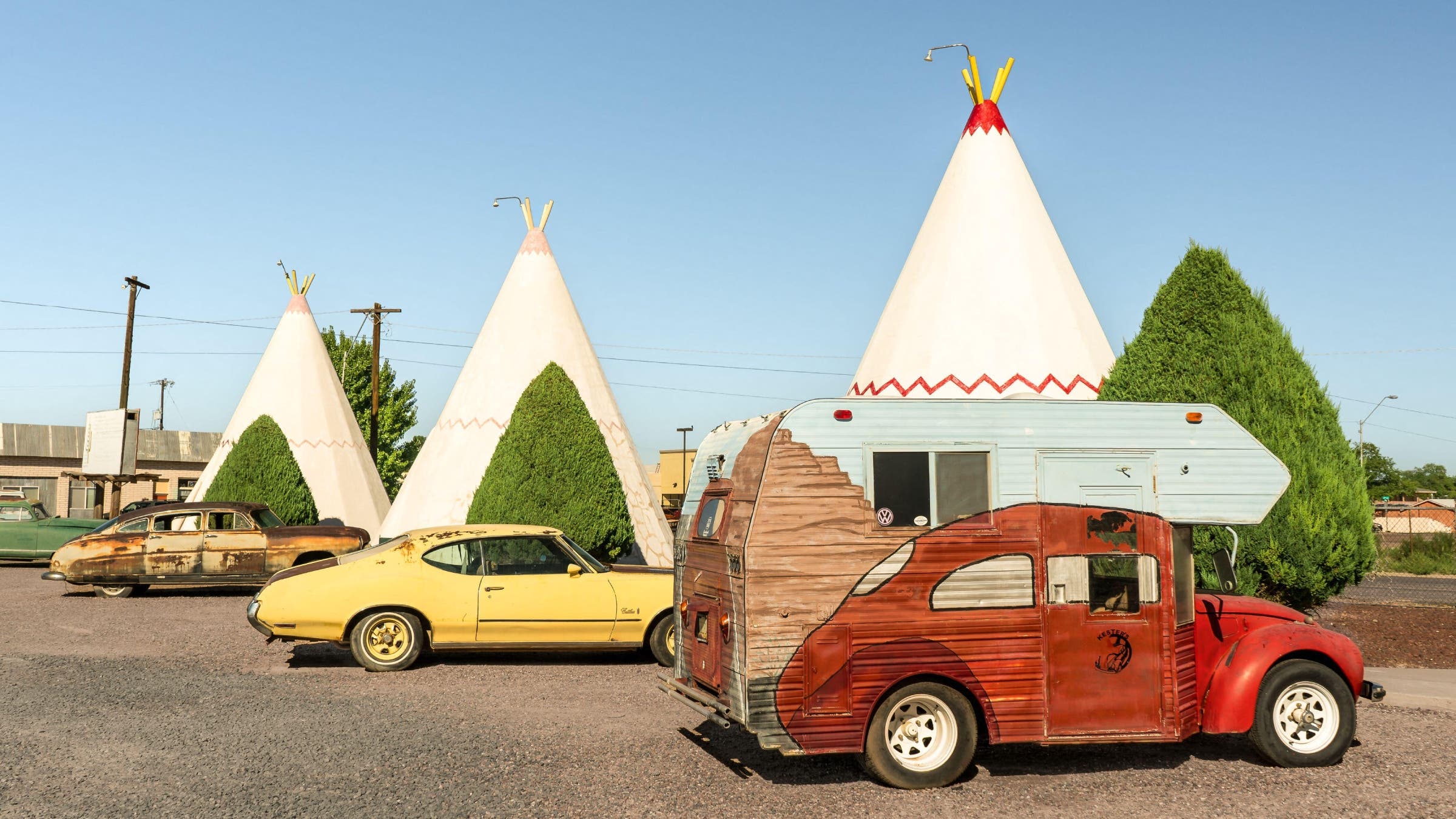 Classic cars in front of fake wigwams.