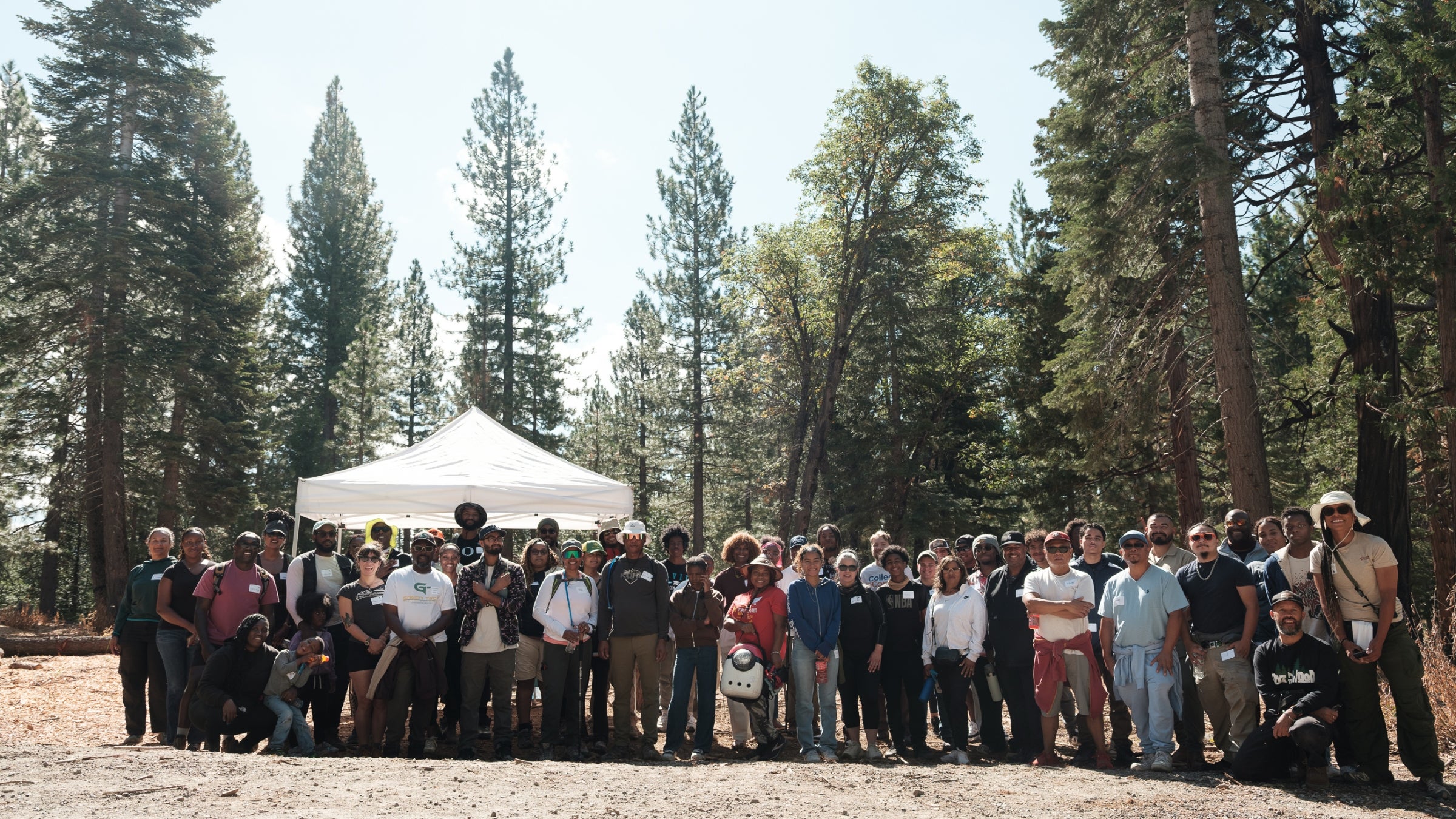 Group of people standing in a wooded clearing.
