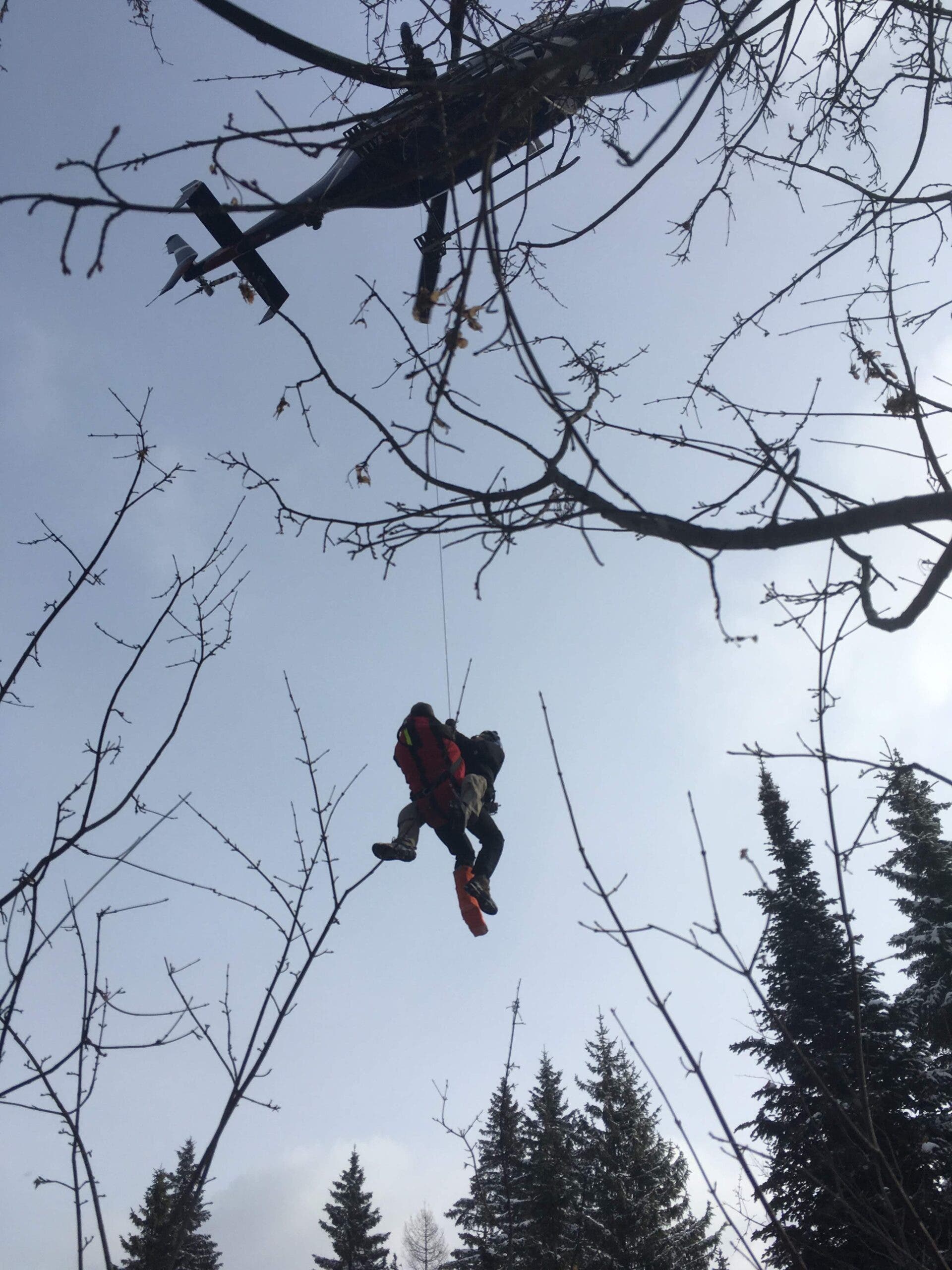 Broste is shown being hoisted out of the woods by helicopter