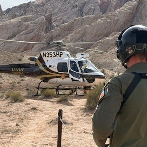 the back of a search and rescue responder is shown against the backdrop of a SAR helicoptor